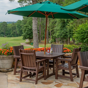 Outdoor dining set with table and chairs under a green umbrella in a garden setting.
